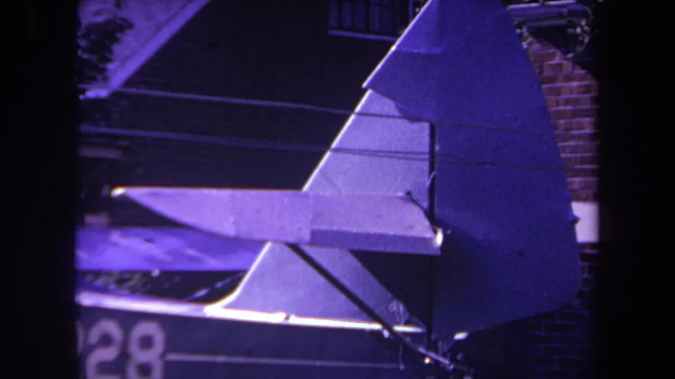 1969 Yucaipa 8mm frame showing the homebuilt airplane's triangular rudder and stabilizer with partial registration numbers visible along the lower fuselage area.