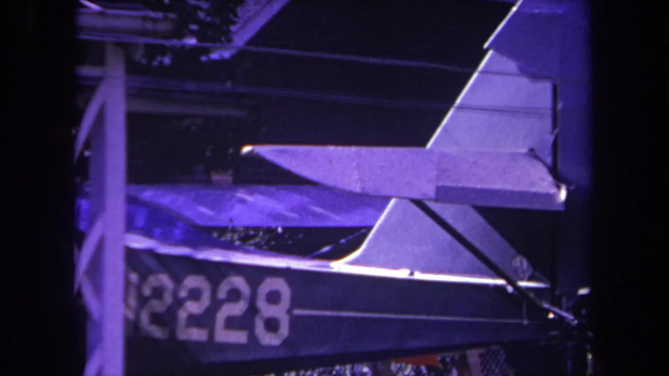 1969 Yucaipa home-movie frame showing a small aircraft parked under a covered structure, with N2228 visible on the fuselage.