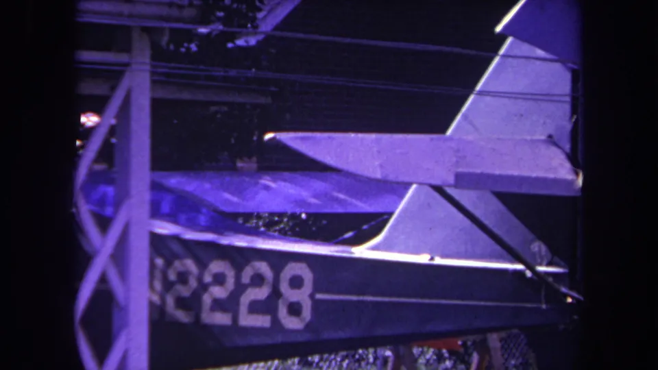 Purple-tinted 8mm frame from Yucaipa showing the side and tail of a small parked aircraft marked N2228.