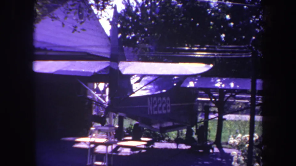 Small single-engine airplane with registration markings parked in shade under a covered structure in Yucaipa, California.