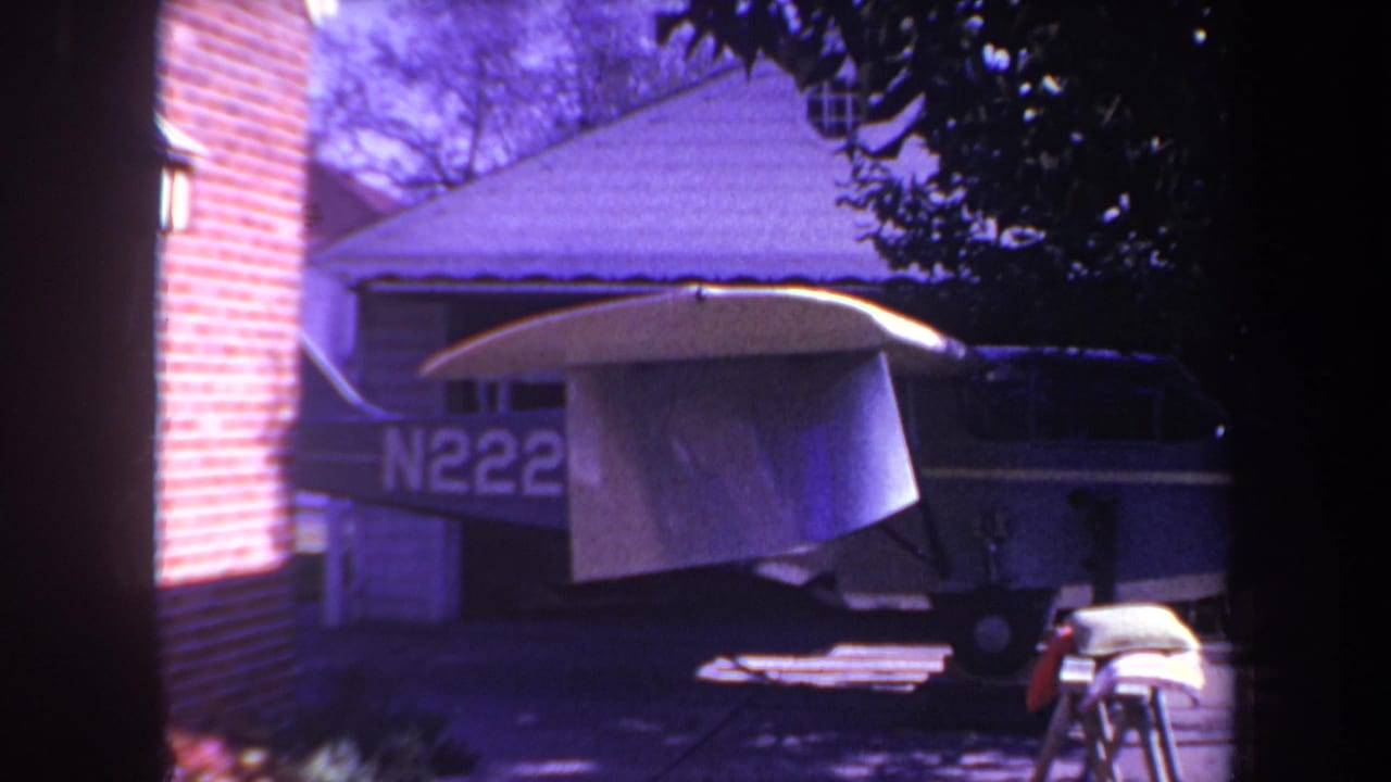 Parked airplane with registration letters partly visible behind a tarp-covered wing.