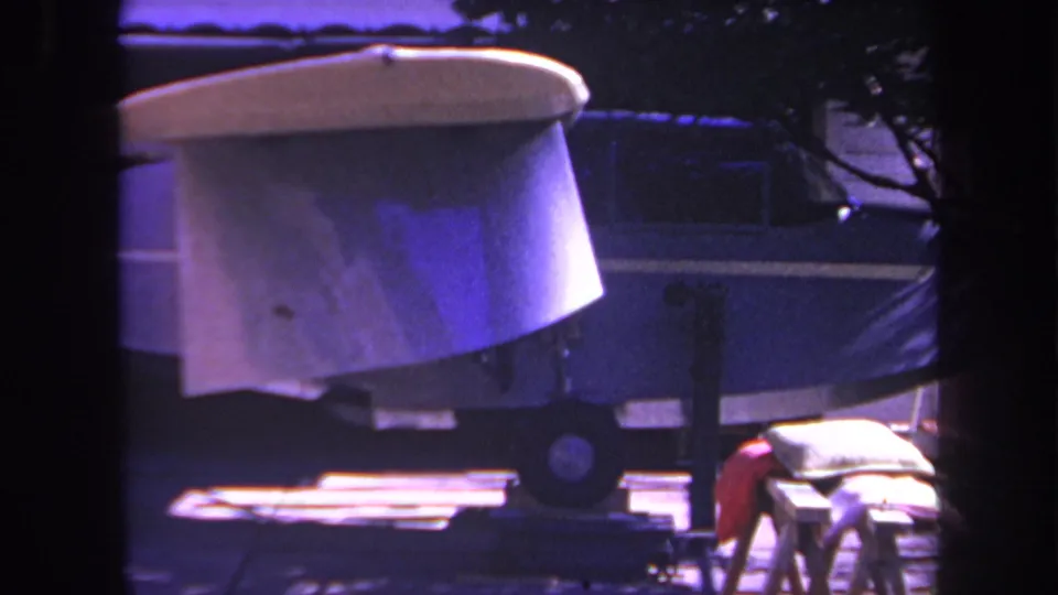 This 1969 Yucaipa home-movie frame gives a closer look at the pale aircraft surface above a blue fuselage or trailer section, with the driveway and support blocks partly visible below.