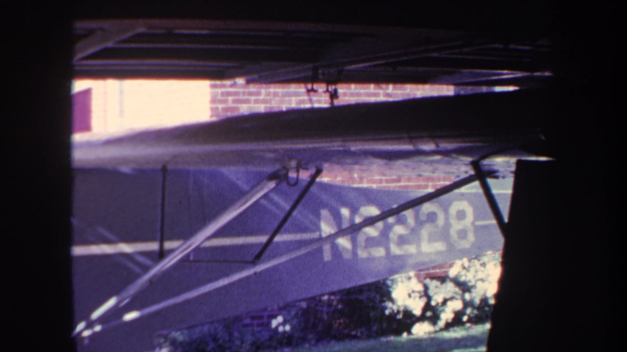 Side of a small aircraft with N2228 visible beneath an overhead garage structure.