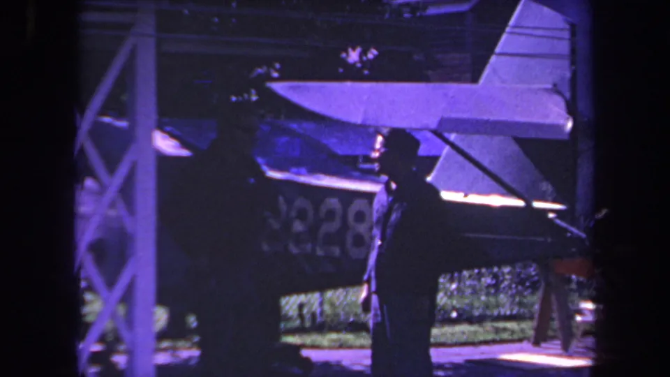 1969 Yucaipa frame showing a man in profile beside a small private airplane, with registration area partly visible.