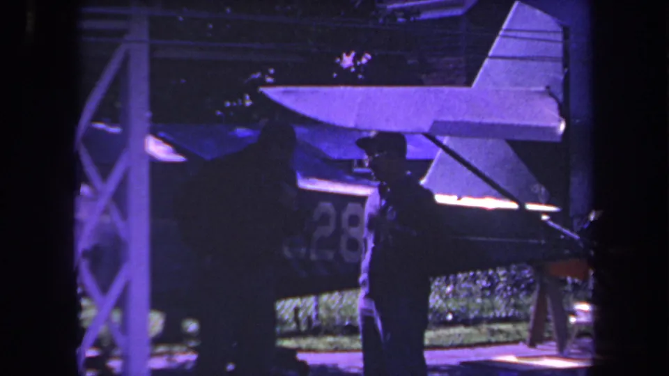 1969 Yucaipa frame showing a silhouetted man and another adult near a small aircraft with visible tail markings.
