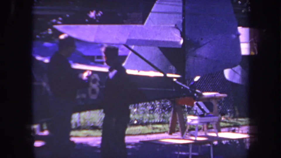 1969 Yucaipa frame with two men standing near a small aircraft tail, rudder, and partial number marking in a yard.
