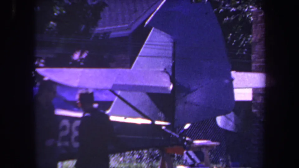 1969 Yucaipa home-movie frame focused on the small aircraft tail, with one man nearby and a partial number visible on the fin.