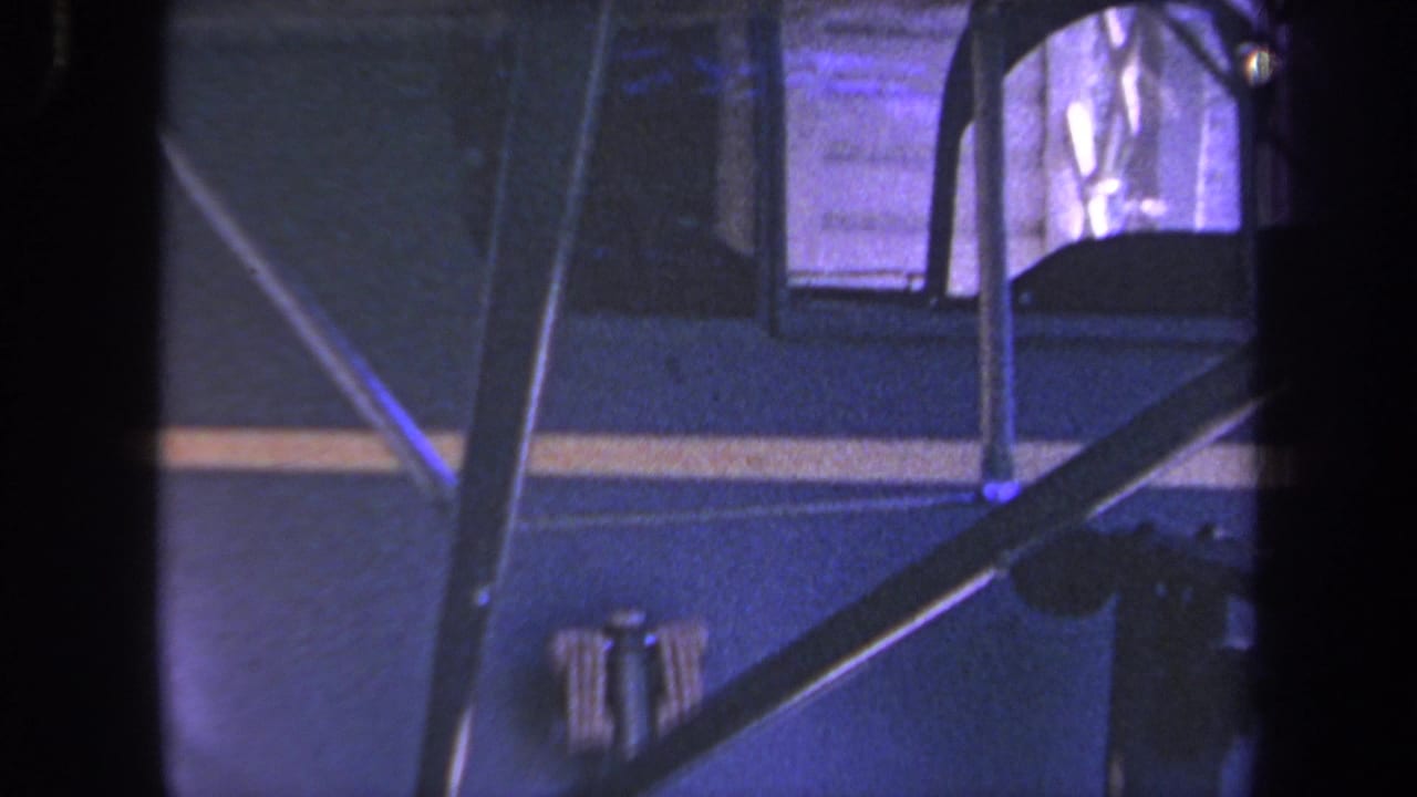 1969 Yucaipa-area 8mm frame showing the side of a blue small aircraft with yellow stripe, struts, and cockpit glazing.