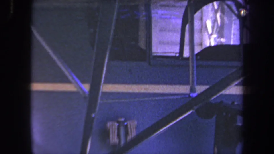 1969 Yucaipa-area 8mm frame showing the side of a blue small aircraft with yellow stripe, struts, and cockpit glazing.