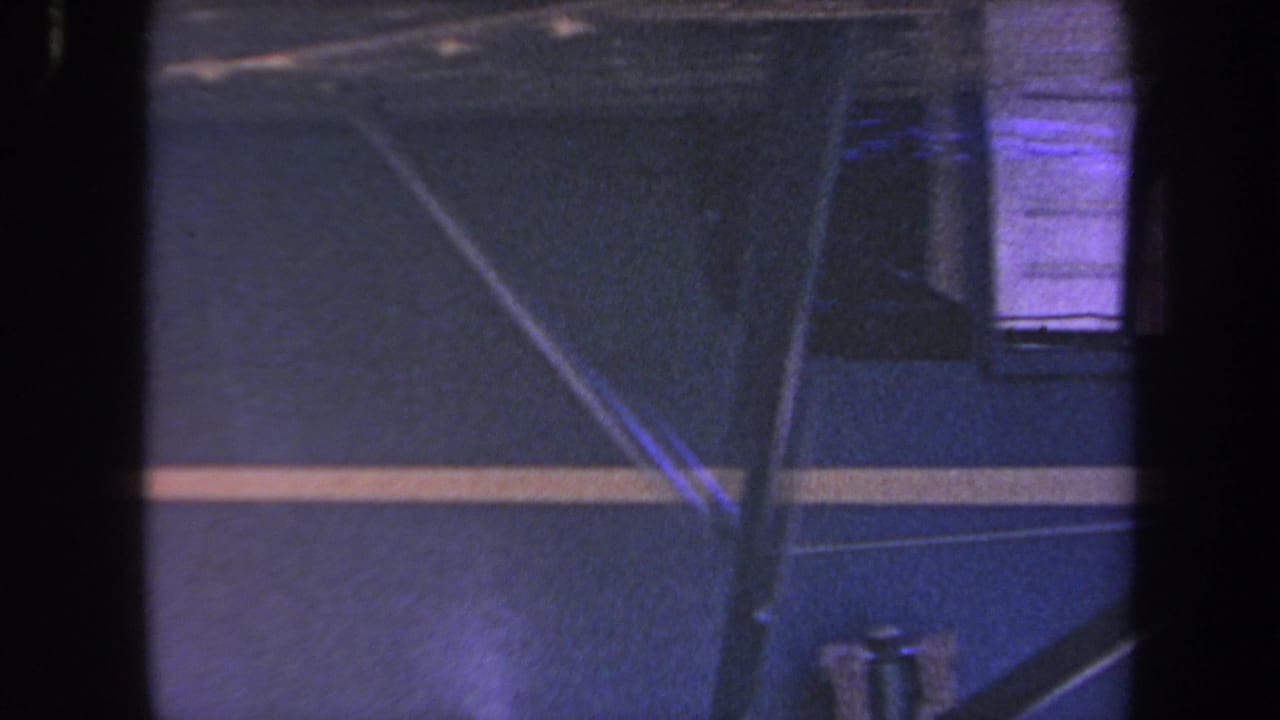 Blue aircraft side with yellow stripe, struts, cockpit window, and dark vertical obstruction.