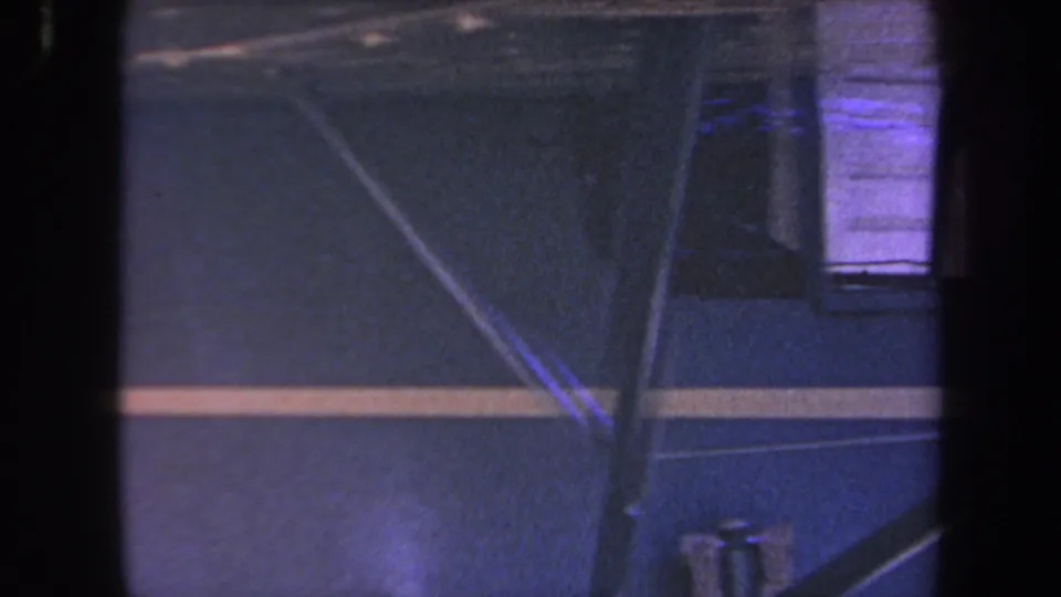 Close 8mm view of the blue aircraft exterior, with yellow striping and cockpit window partly blocked by a dark foreground edge.