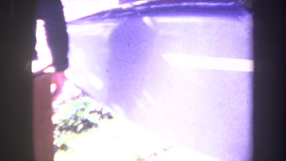 1969 Yucaipa frame with the man's arm and legs beside a light blue surface, grass, and overexposed driveway ground.