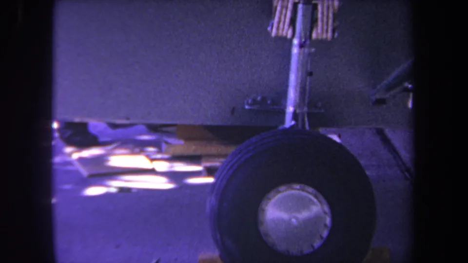 Close 8mm view of a small plane landing wheel and strut, likely at the Yucaipa, California airfield location noted in the clip metadata.
