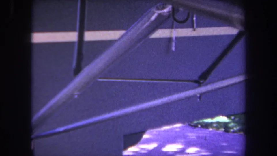 Close 1969 California home-movie view of light aircraft struts crossing a dark fuselage with a pale horizontal stripe.