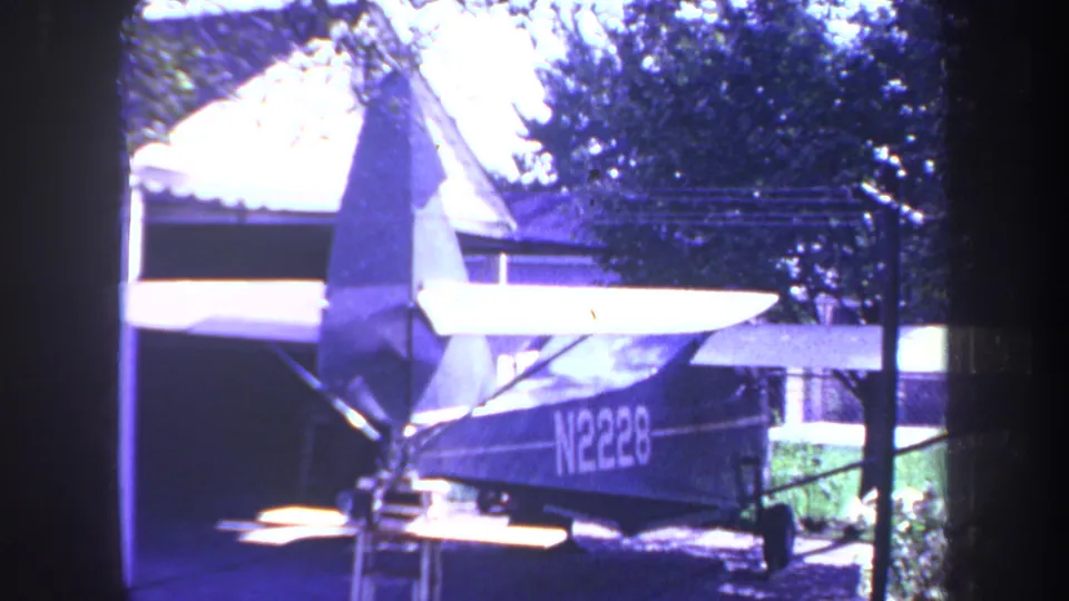 Rear view of the small aircraft beside a garage or house exterior, with registration N2228 visible on the fuselage.