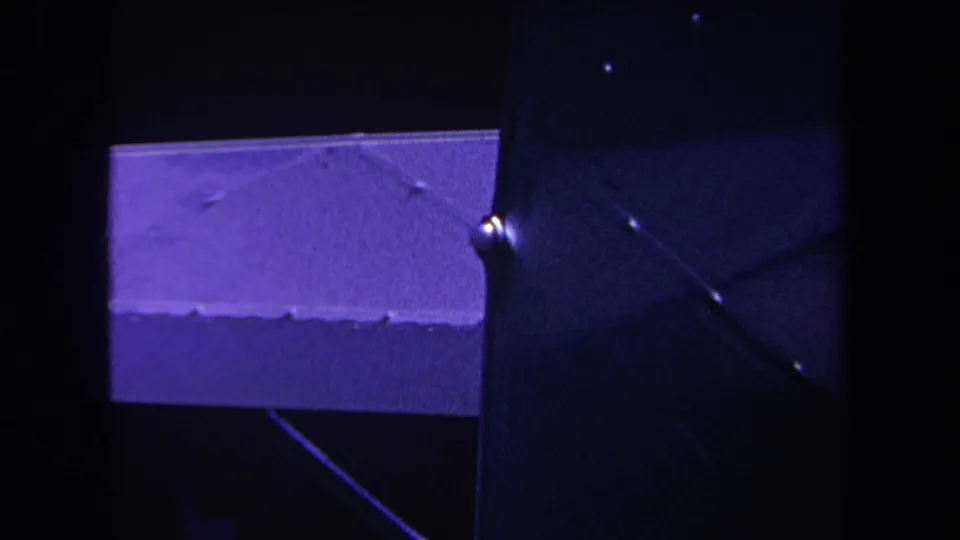 Purple-tinted 1969 8mm close-up showing a metal aircraft section, a round fitting, and adjoining structural lines.