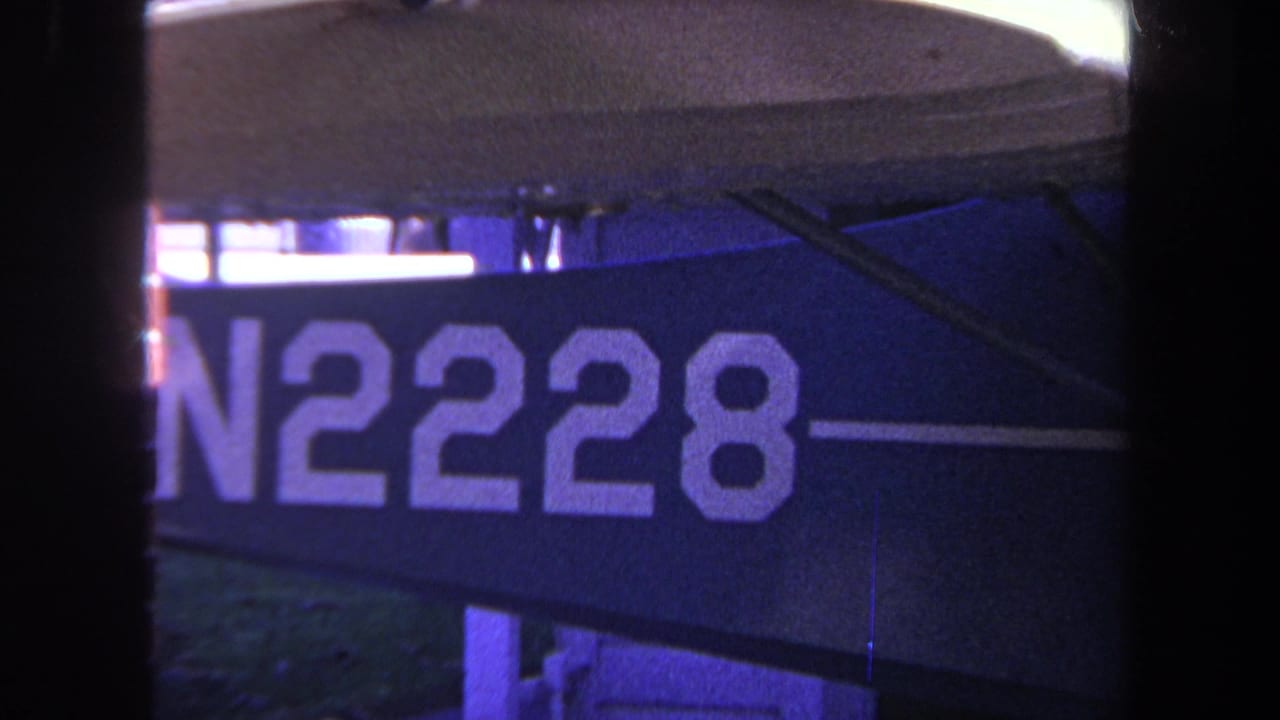 Close-up of white N2228 lettering on a dark blue sign with metal supports and black frame edges.