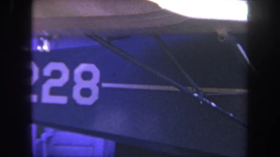 1969 Yucaipa 8mm frame showing cropped N2228 lettering, a white stripe, and diagonal metal supports on the sign surface.
