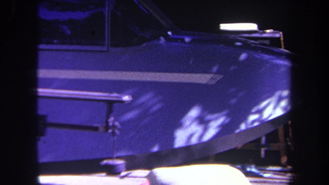 1969 home-movie frame from Yucaipa, California, showing the blue nose and cockpit area of a parked small airplane in bright sun.