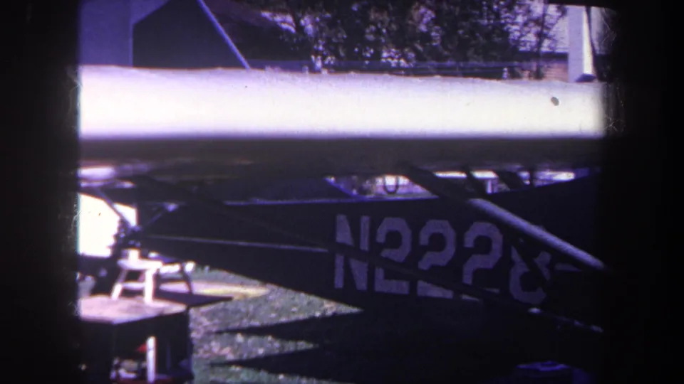 Close 8mm frame of the blue airplane's lower side in Yucaipa, California, with a partial registration number visible in shadow.