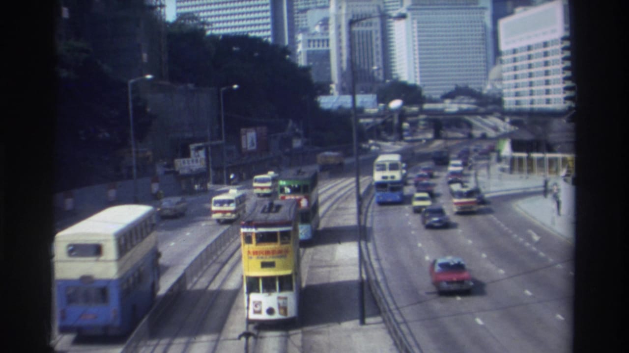 Elevated view of Hong Kong traffic with buses, cars, tram tracks, and high-rise buildings.