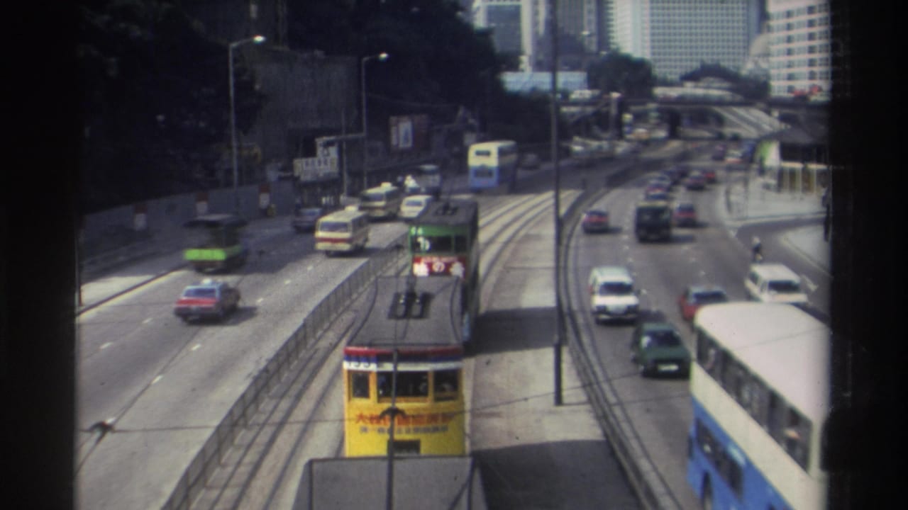 Yellow tram approaches below an elevated viewpoint as cars and buses travel on adjacent lanes.