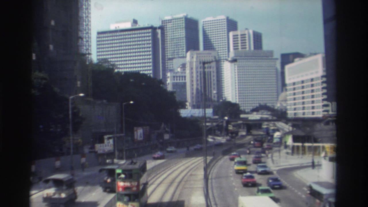 Cars and public transport move along curved roads beneath tall buildings.