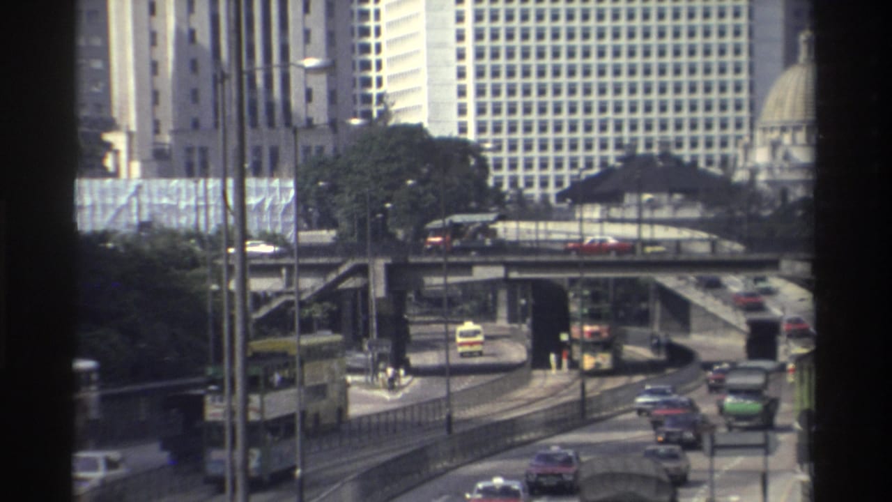 Cars and buses travel along elevated roads with a grid-window high-rise and domed structure behind them.