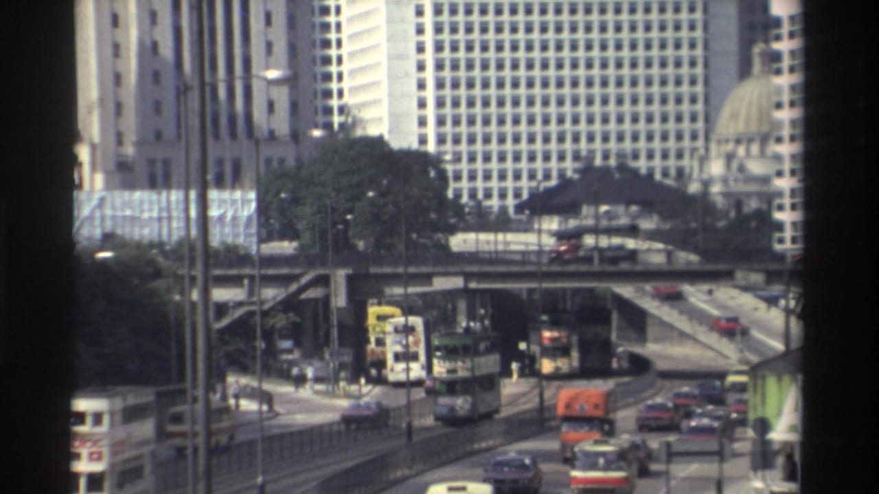 Elevated Hong Kong roadway with buses, cars, towers and a domed building in the background.