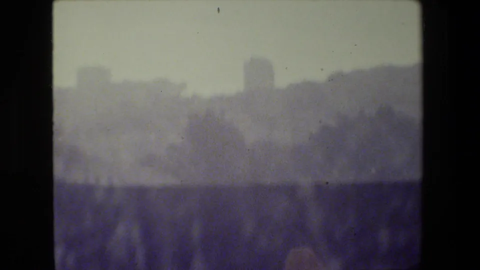 Heavily blurred 1984 San Francisco frame with indistinct waterfront or hillside shapes and a dark band across the lower portion.