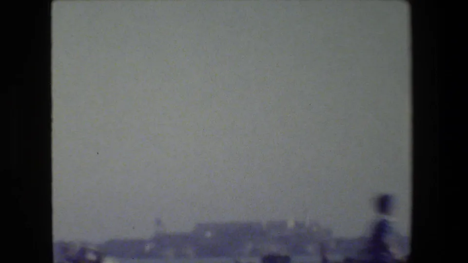 Soft, hazy 8mm view toward a distant San Francisco shoreline or hill, with foreground detail mostly blurred by motion.