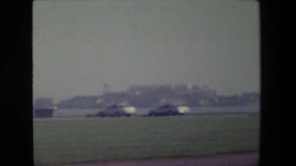 1984 San Francisco waterfront view across a grassy field toward a hazy shoreline and low distant landforms.