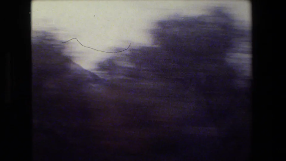 Soft, violet-shifted 8mm frame showing blurred hilly terrain and pale sky during a moving road-trip view.
