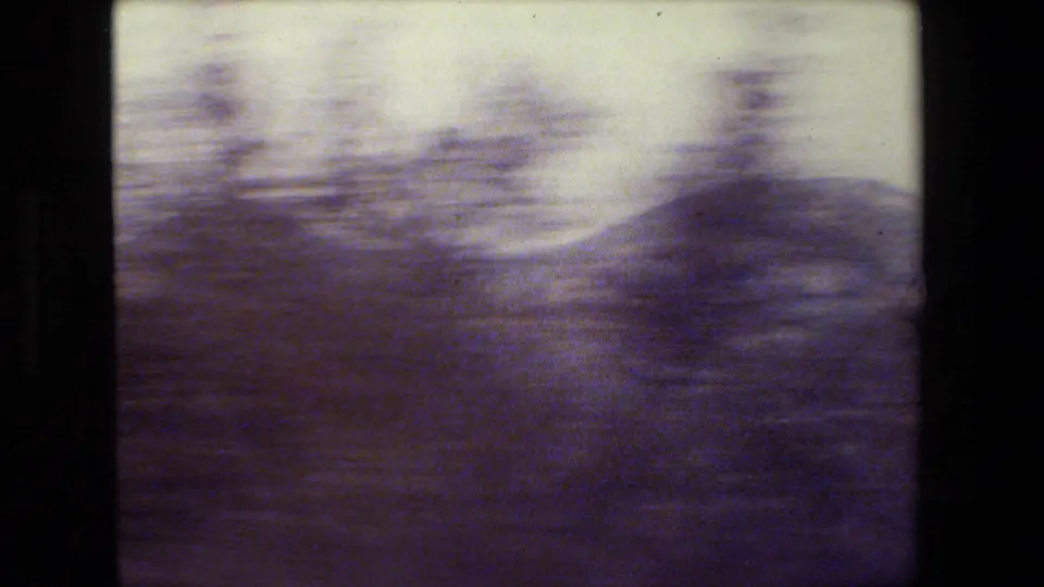 Final 8mm frame showing a motion-blurred hillside, scattered trees, and pale sky, consistent with a moving California road-trip view.