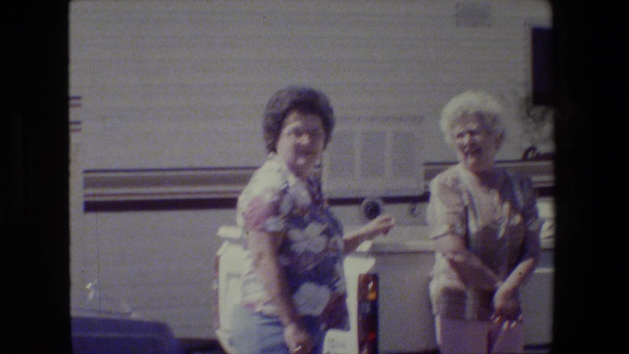 Two older women in casual clothing appear to laugh and talk beside a white recreational vehicle in 1984 California home-movie footage.