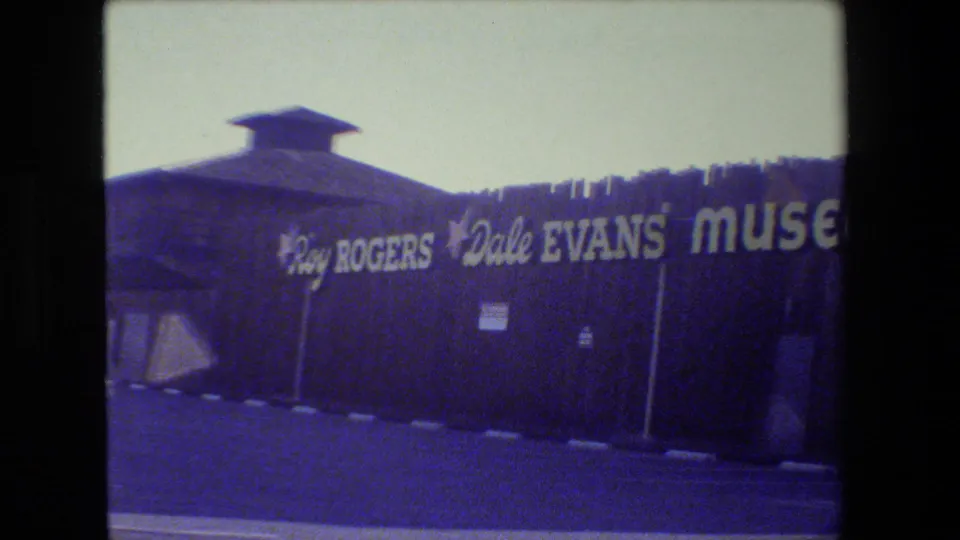 1984 8mm frame of the Roy Rogers and Dale Evans Museum exterior in San Francisco, with sign, facade, and paved lot visible.