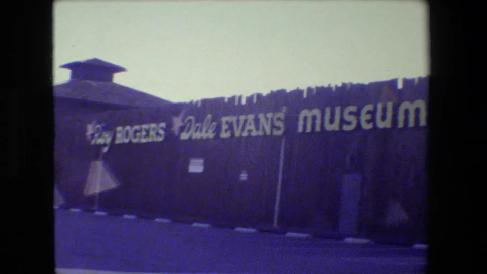 1984 8mm frame showing the Roy Rogers Dale Evans Museum facade in California with bold white lettering on a dark exterior wall.
