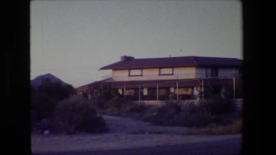 Drive-by view of a two-story residential exterior in the supplied 1984 San Francisco home-movie footage.