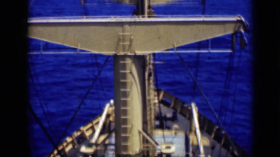 Elevated shipboard view showing mast supports, rigging, deck railings, and blue ocean in 1946 8mm home-movie footage.