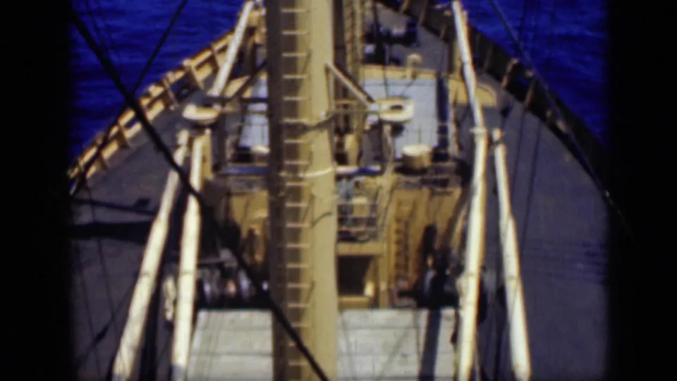 Elevated 1946 ship deck view with the mast and ladder in the center, rigging lines crossing the frame, and blue water around the vessel.