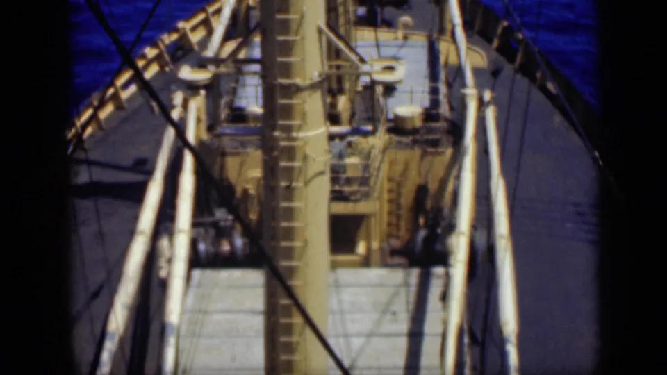 1946 8mm home-movie frame showing a ship deck from above, with mast, rigging, railings, and dark window-like borders.