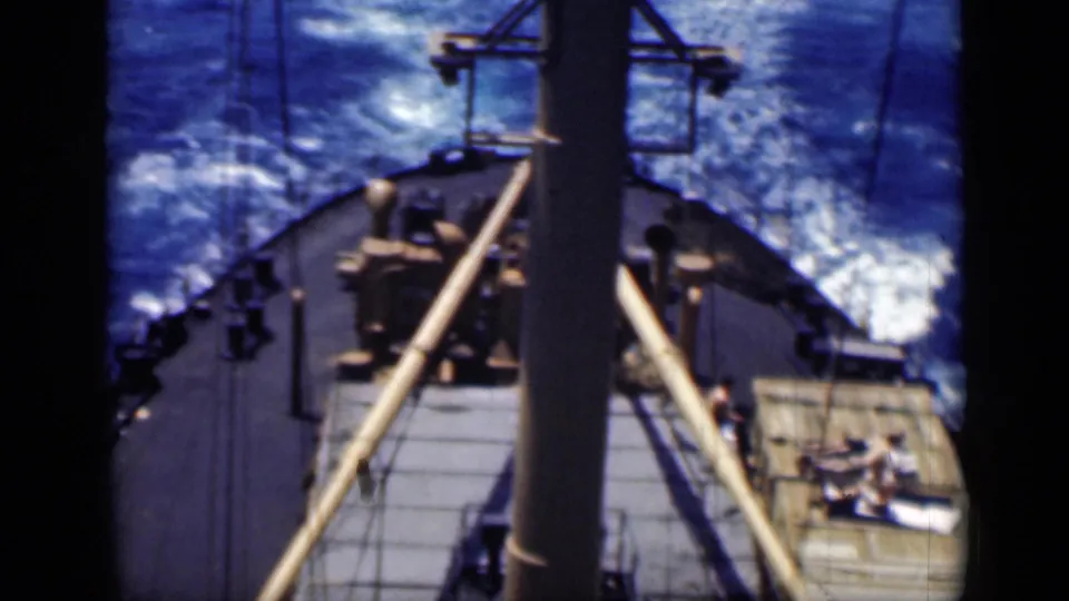 Elevated 1946 Cairo view across a ship deck, showing the mast, rigging, bow area, blue water, and small figures on the deck.