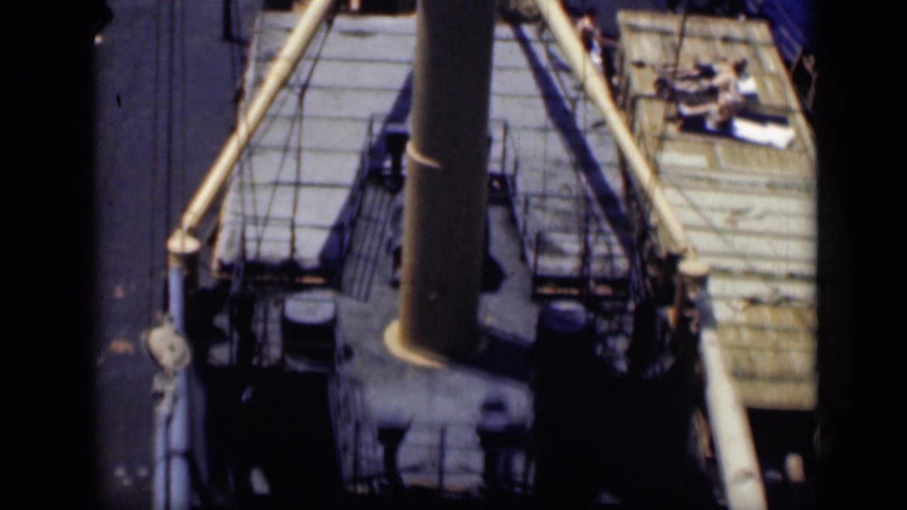 1946 Cairo shipboard frame with mast and rigging in the foreground, deck equipment below, and people gathered on a right-side deck area.