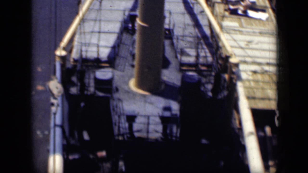 Ship deck seen from above with railings, deck equipment, and a central stack or mast.
