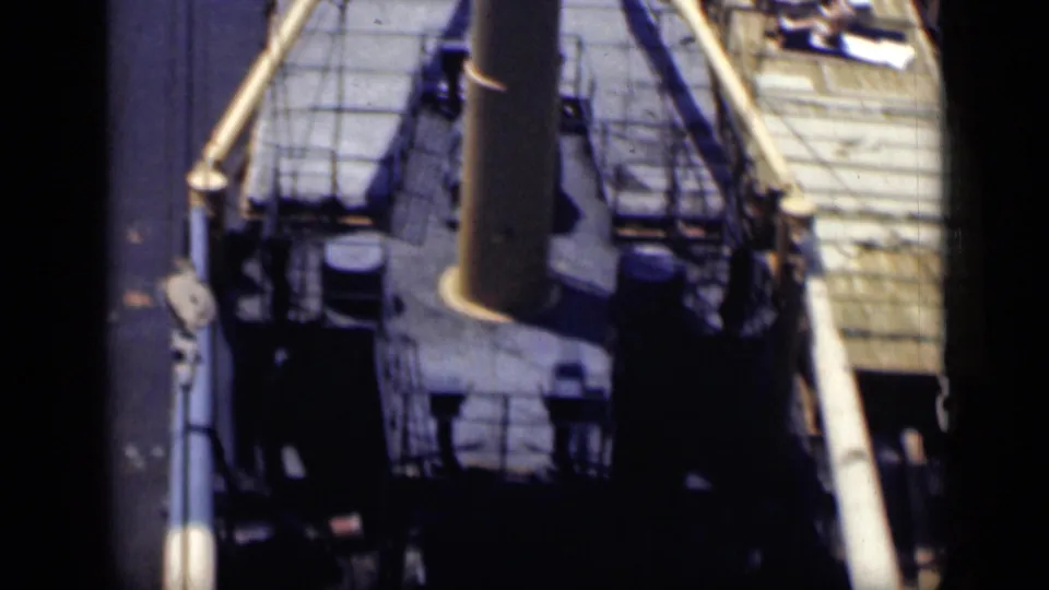 1946 8mm travel footage shows an elevated view over a ship deck with railings, equipment, and a prominent central stack or mast.