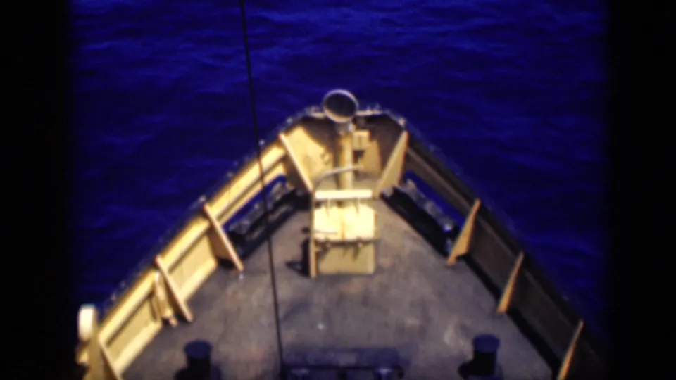 1946 8mm footage shows the ship's bow from above as it faces deep blue open water, with railings and deck hardware visible.