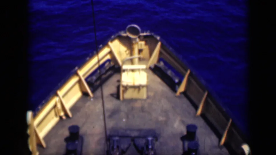 The ship's bow deck appears in 1946 8mm footage, with railings, bollards, and blue sea surrounding the forward view.