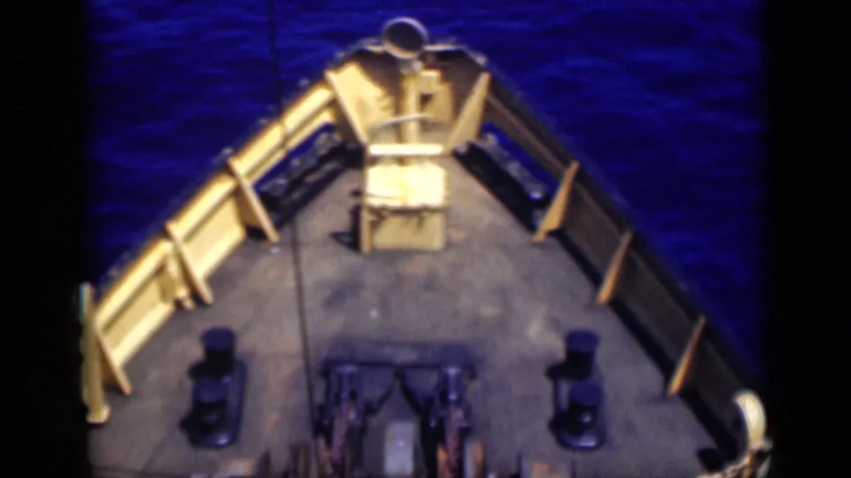 A closer 1946 8mm bow view shows railings, bollards, deck hardware, and deep blue ocean water around the ship.