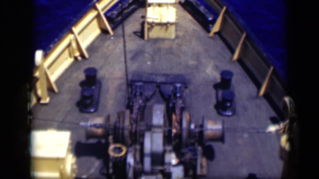 1946 Egypt 8mm frame showing more of the working deck, including winches, large spools, railings, bollards and blue sea along both sides.