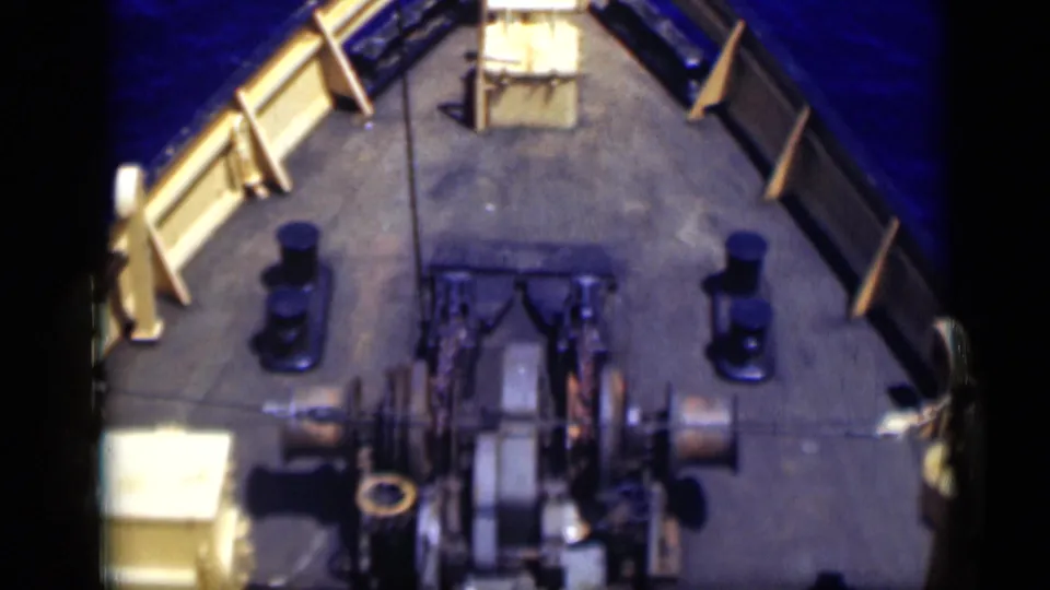 1946 Egypt 8mm frame showing more of the working deck, including winches, large spools, railings, bollards and blue sea along both sides.